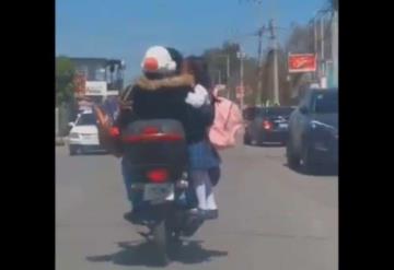 Hombre transporta a una niña parada en el escape de una motocicleta