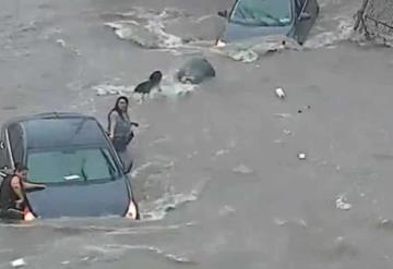 Video: Mujer queda atrapada en calle inundada y coladera se la traga