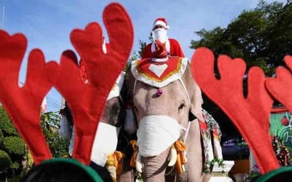 Santa Claus regala cubrebocas montado en elefante