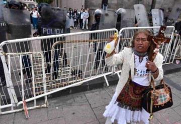 Mujer con crucifijo en mano rocía agua bendita a feministas durante marcha